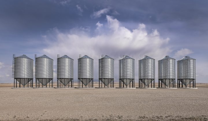 A row of steel grain storage bins near the village of Herronton, Alberta, Canada