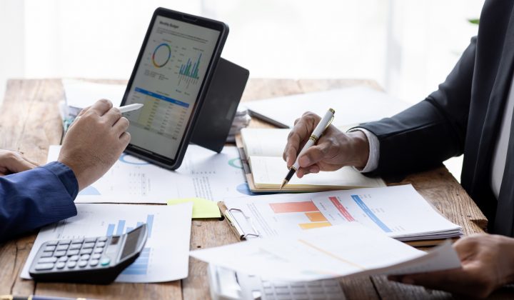 Group of confident business people point to graphs and charts to analyze market data, balance sheet, account, net profit to plan new sales strategies to increase production capacity.