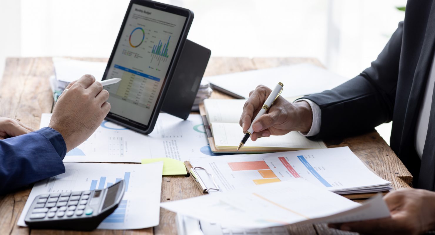 Group of confident business people point to graphs and charts to analyze market data, balance sheet, account, net profit to plan new sales strategies to increase production capacity.